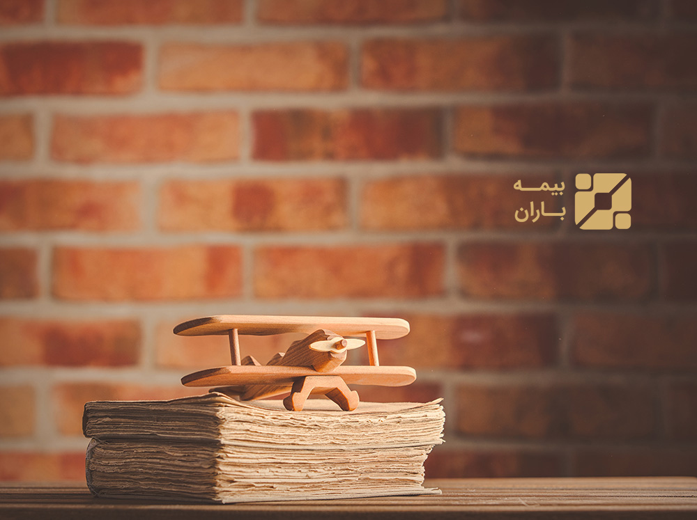 Vintage wooden airplane toy and old books on wooden table at brick wall background. Library